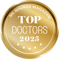 A gold circular badge with the text Milwaukee Magazine Top Doctors 2025 and five stars along the bottom edge.