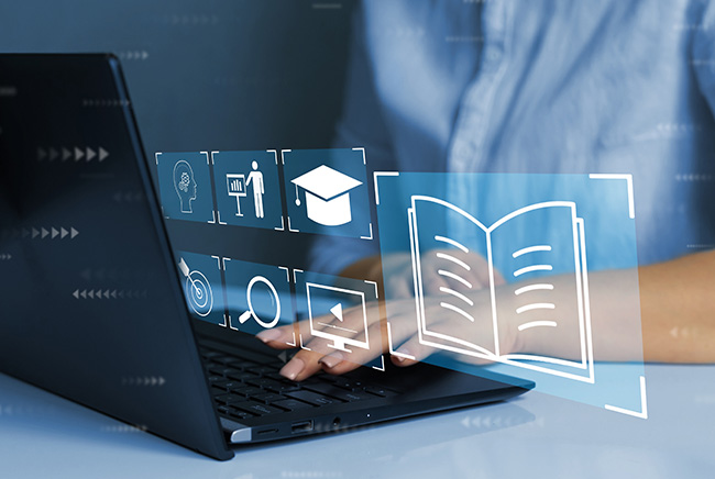 A person typing on a laptop with digital education and learning icons, such as a graduation cap and open book, appearing as holograms above the keyboard.